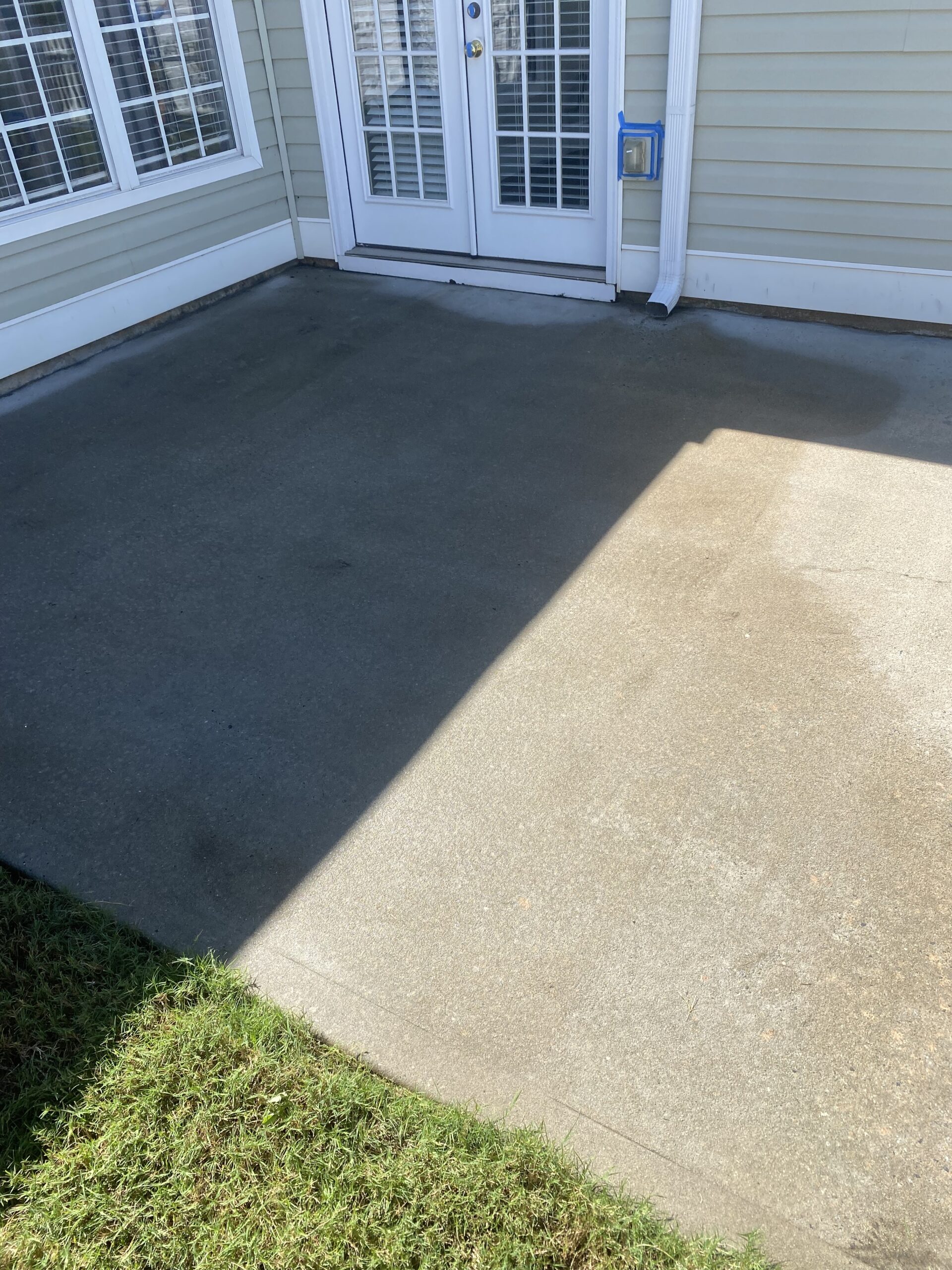 Sunlit concrete patio outside glass French doors