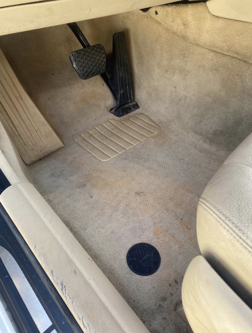 Beige car footwell with pedals and carpet