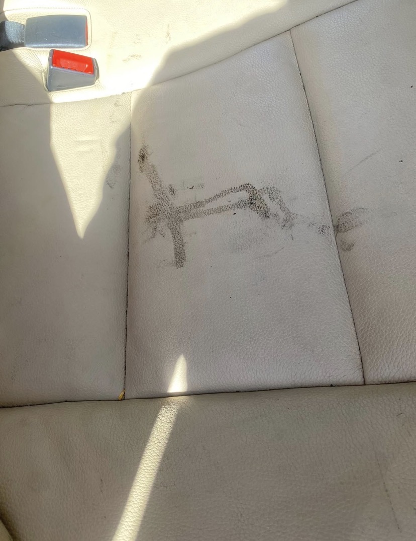 Stained beige leather car seat with scuff marks