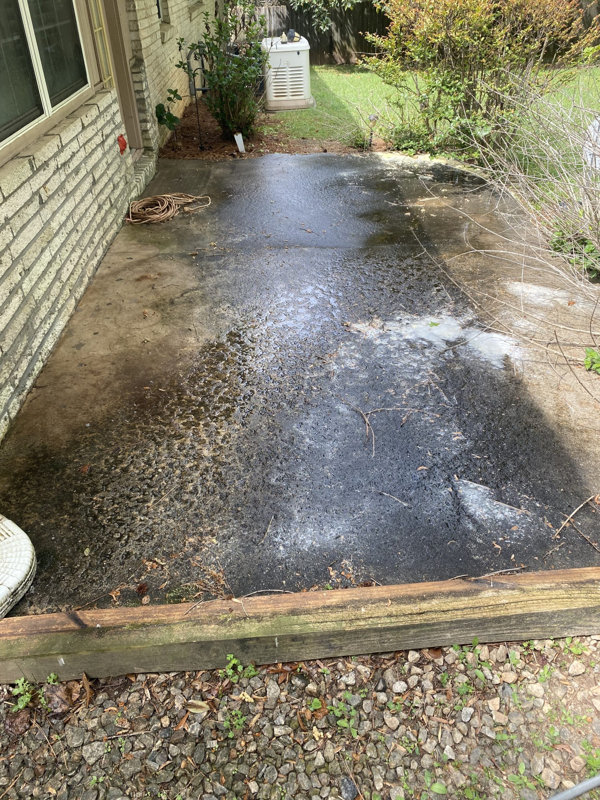 Wet stained concrete patio beside house