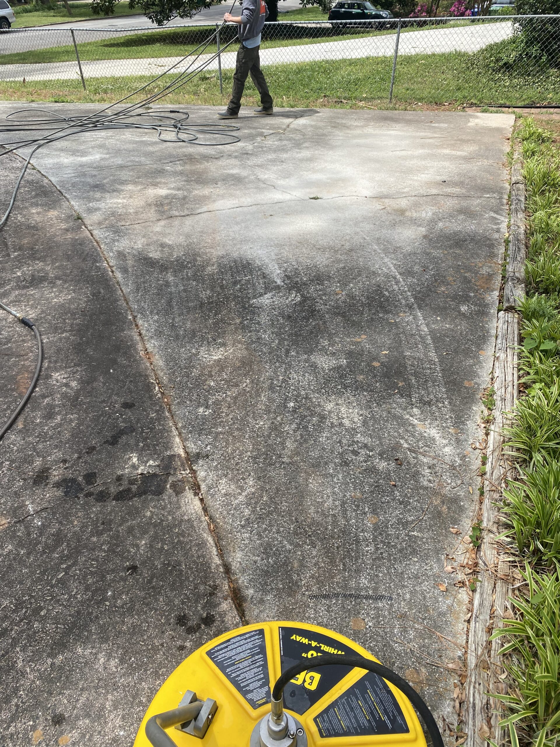 Pressure washing concrete driveway with yellow surface cleaner