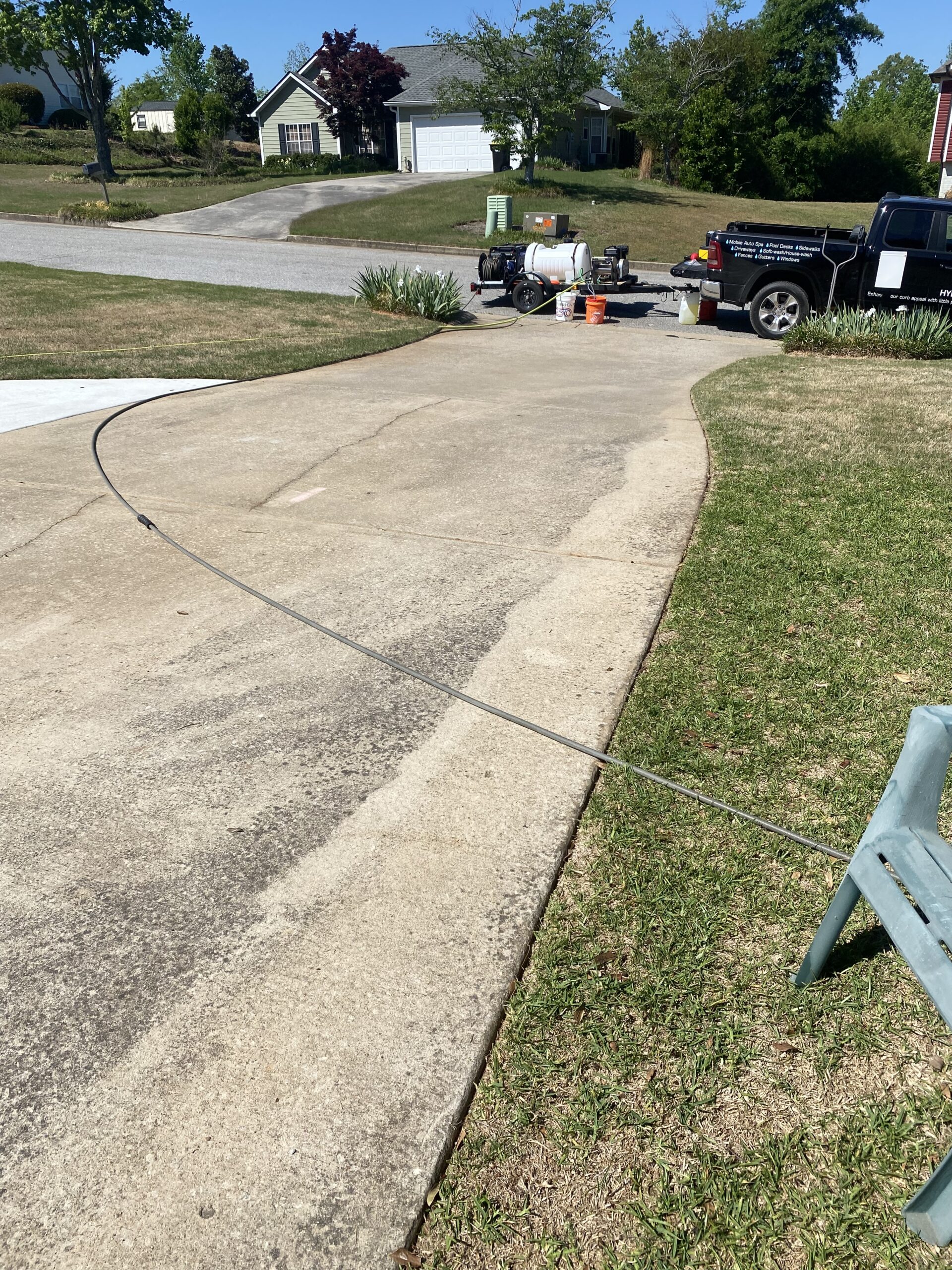 Driveway with pressure washing truck and hose