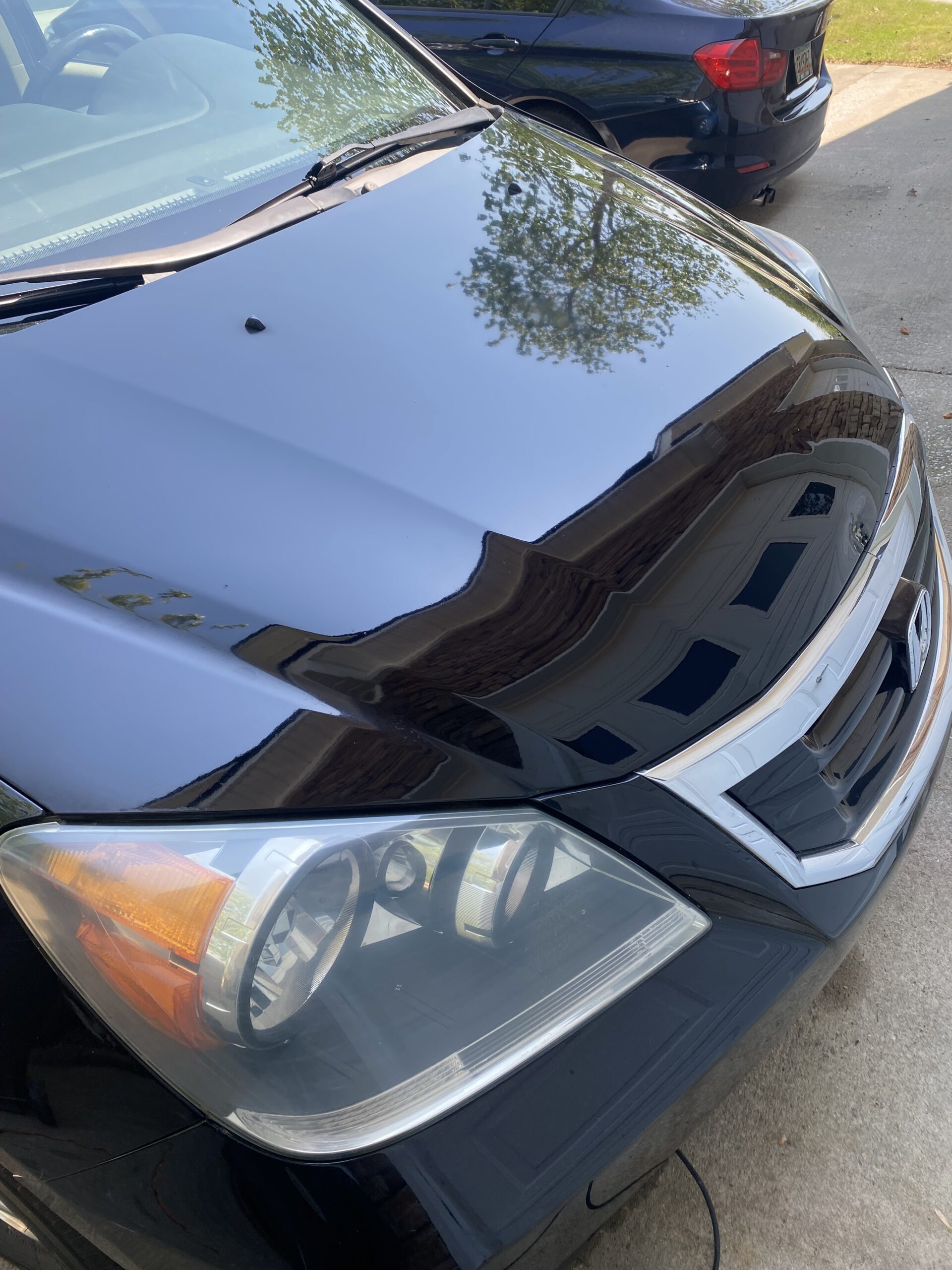 Black car front with reflective hood and headlight