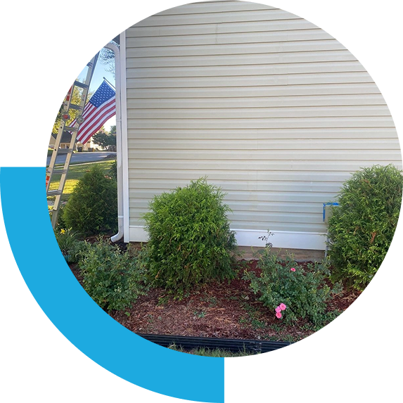 House siding with shrubs and American flag